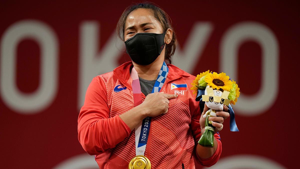 A teary-eyed Hidilyn Diaz points at the Philippine flag on her chest